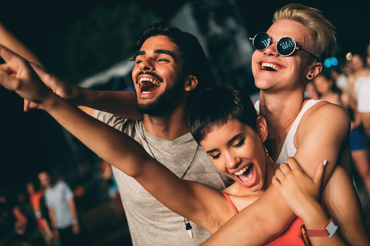 Três amigos, dois homens e uma mulher, reunidos e curtindo um show em um festival de música